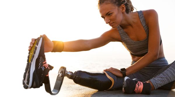 Woman with prosthetic leg stretches before exercise